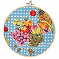 Retro kitchen fruit bowl framed in bamboo hoop with beaded vintage tea towel design hanging on wall