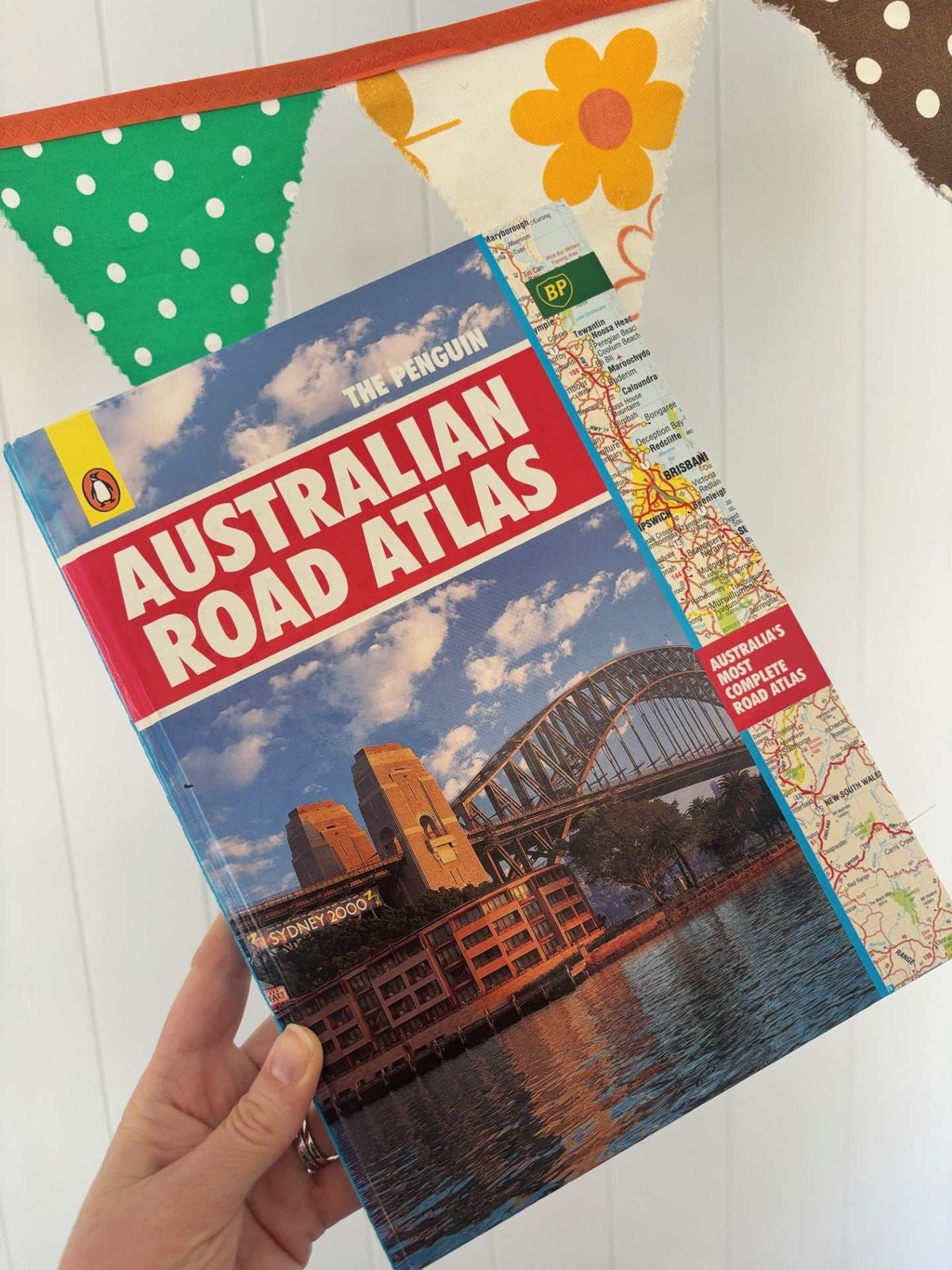 Vintage Australian Road Atlas used to make original wallets by lyssymay held by a hand on a white background
