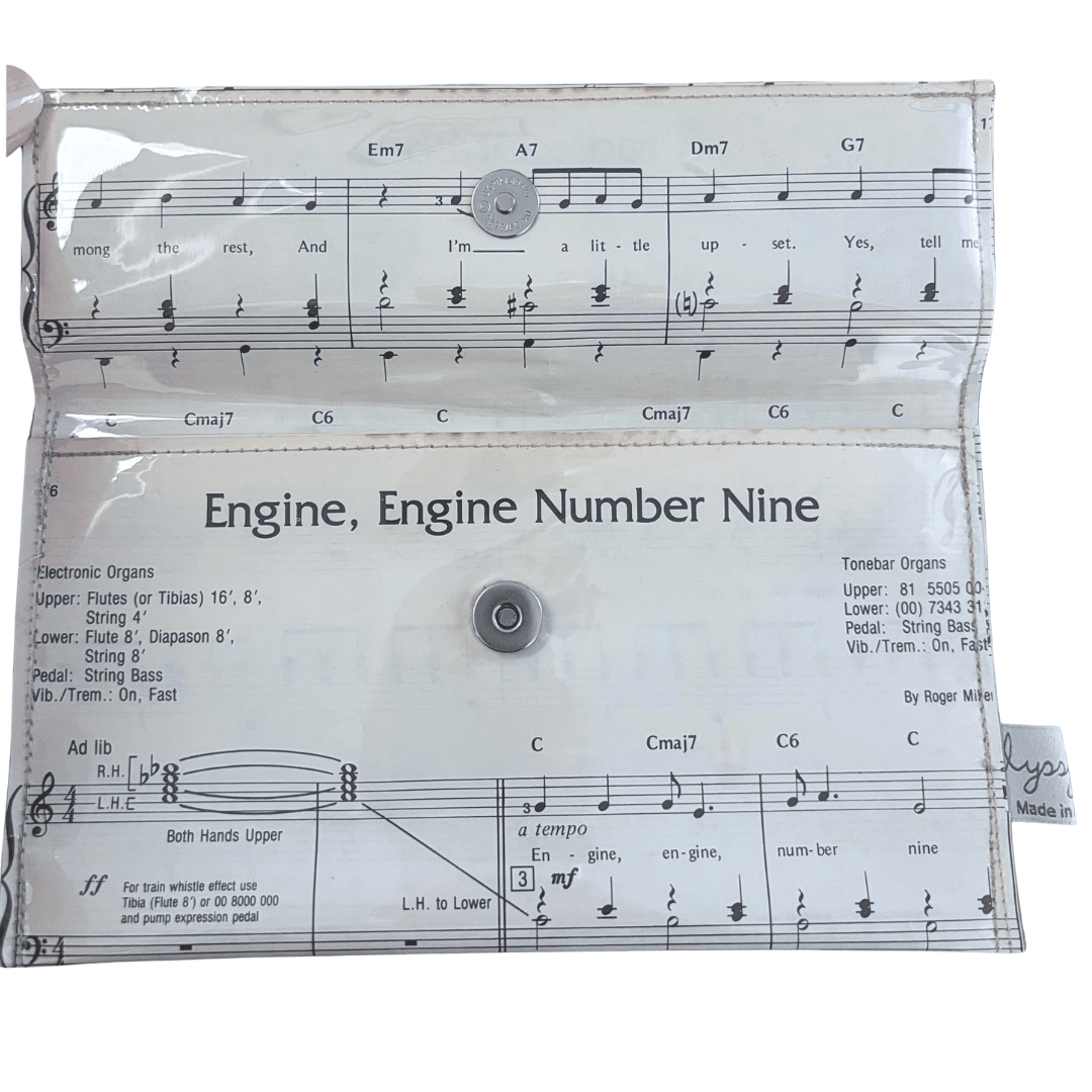 Clear handmade wallet with music sheet design and text 'Engine, Engine Number Nine' on a white background