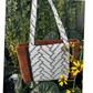 Burnt Caramel Noir handcrafted shoulder bag held in natural light with yellow flowers – Japanese cotton/linen with panel detail – Lyssy May